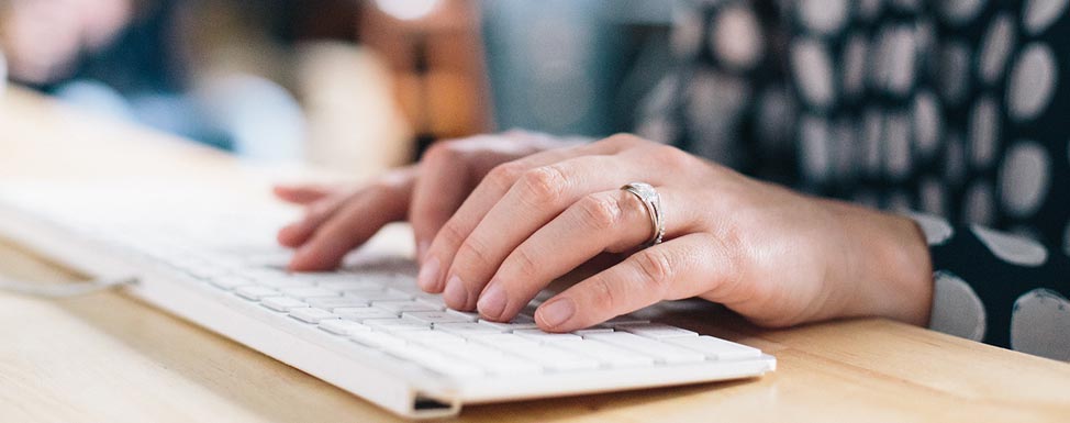 Closeup of woman typing at computer keyboard